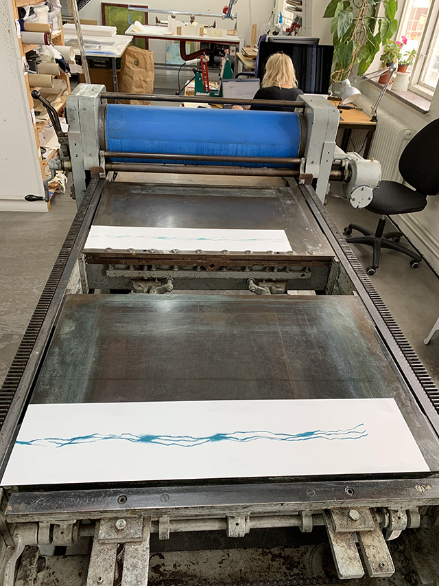offset printing press with a plate and paper on the bed